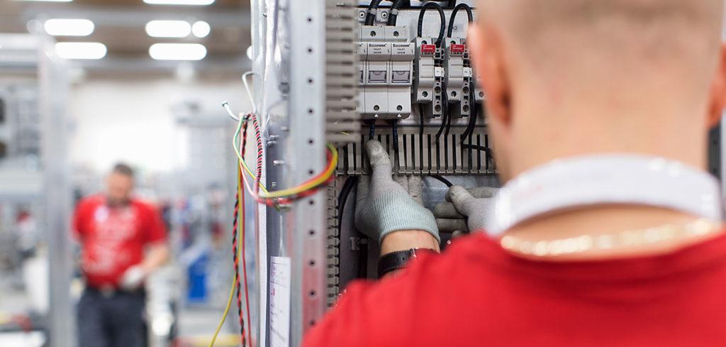 Man photographed from behind working with electrical panel